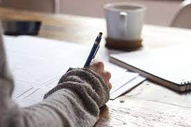 An image of a person writing in a notebook: the image is next to the link for sharing your own U of T story.