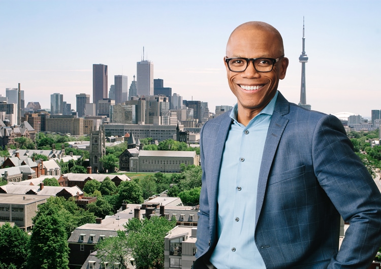 Dr. Everton Gooden smiles while standing on a rooftop overlooking downtown Toronto