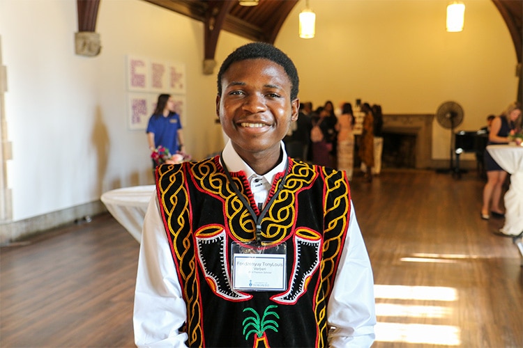 Fondzenyuy TonyLouis Verberi smiles while taking part in a social reception in a large hall.