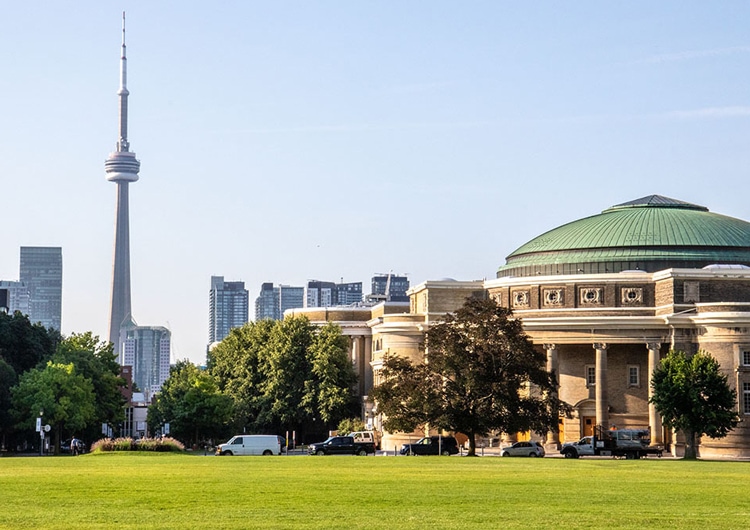 The lawn of Front Campus stretches out towards Convocation Hall, with the CN Tower in the background.