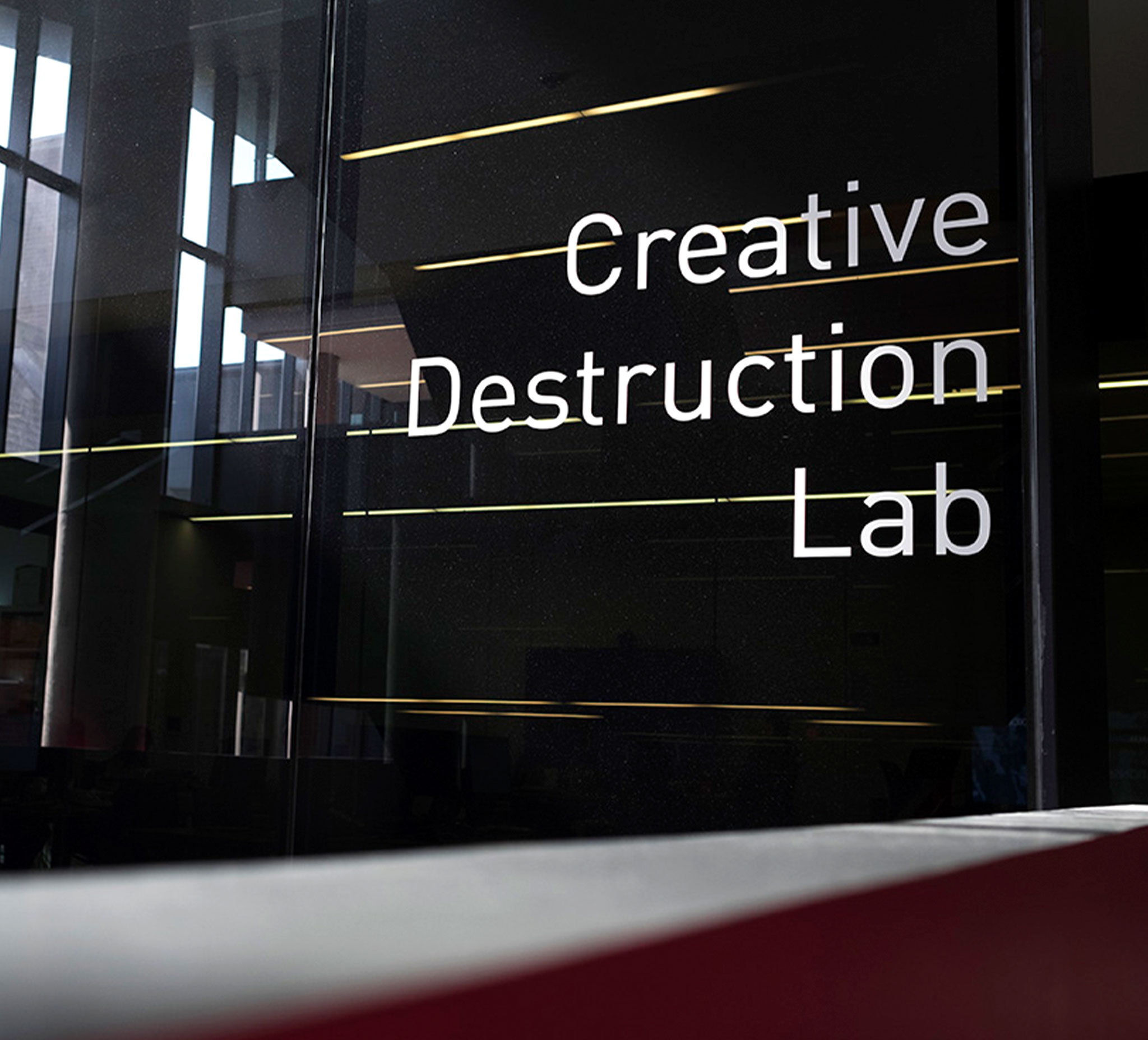 The sun glints off metal letters on a glass wall. They spell out: Creative Destruction Lab.