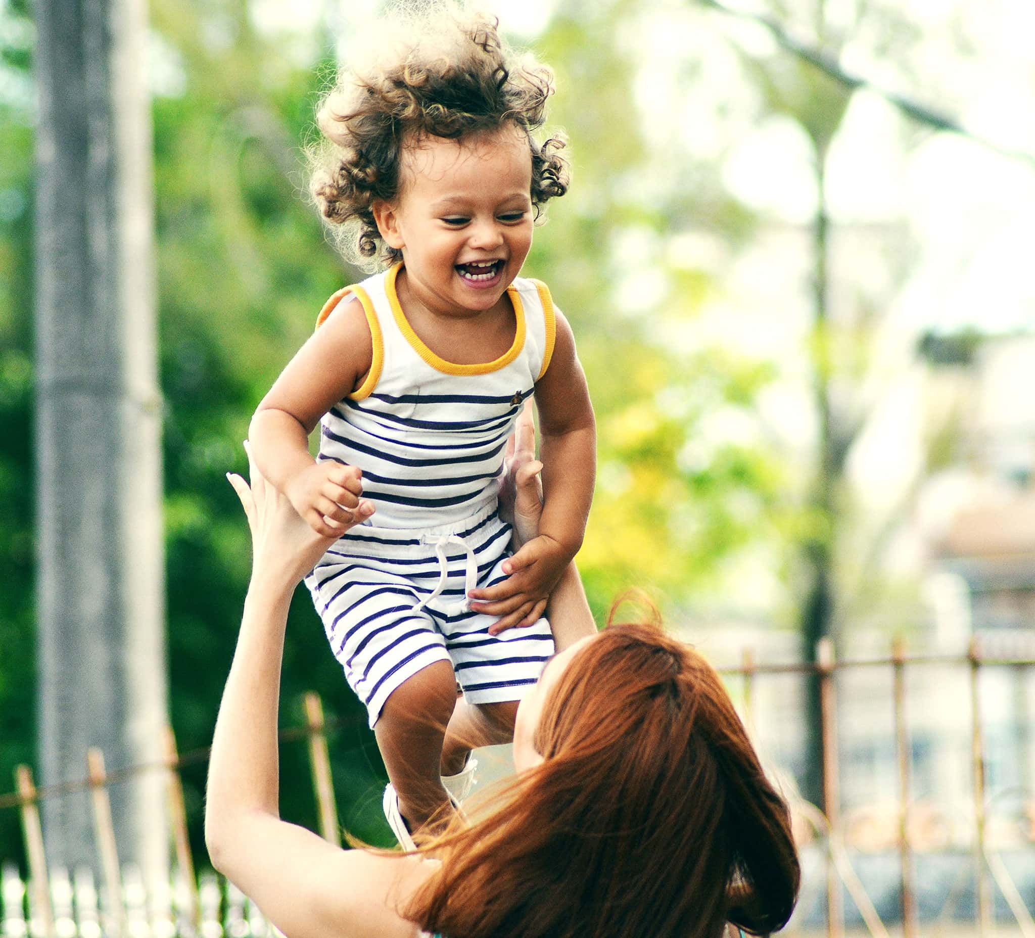 A woman tosses a laughing toddler up in the air.