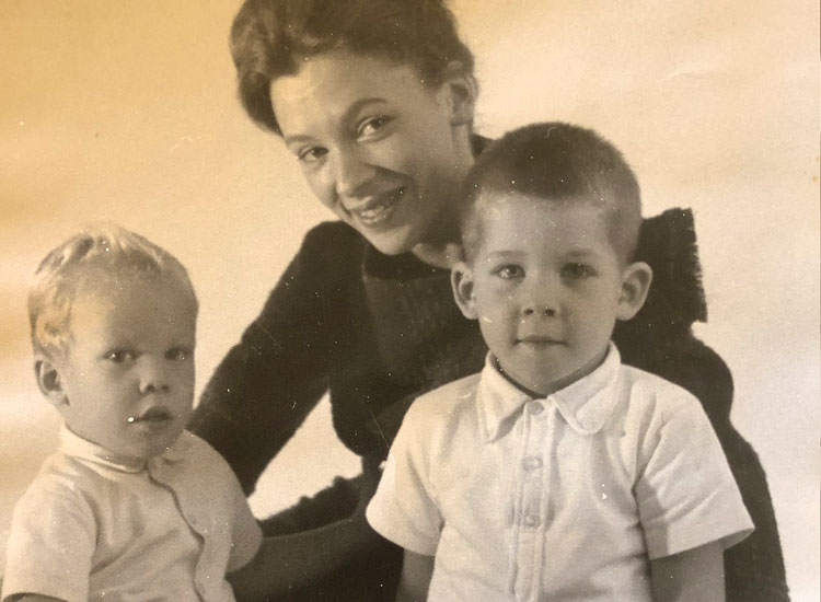 In an old photograph from the 1960s, Joyce Connolly smiles while sitting behind her two small children, James and David