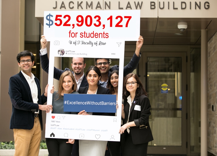 Seven students smile and hold up a banner reading: $52,903,127 for students.