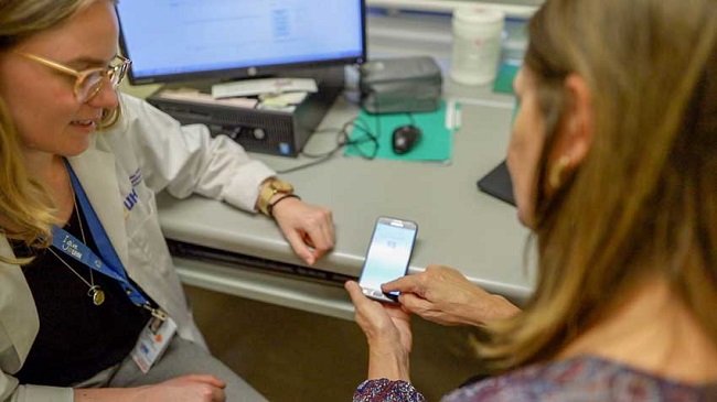 A doctor and a patient look at a smartphone screen together.