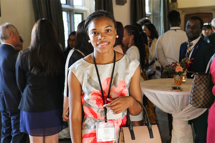 Nikiela Baptiste smiles while taking part in a social reception in a large hall.