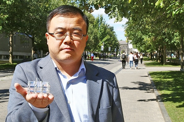 Xinyu Liu stands on King's College Road and holds up a small box made of metal and clear plastic.