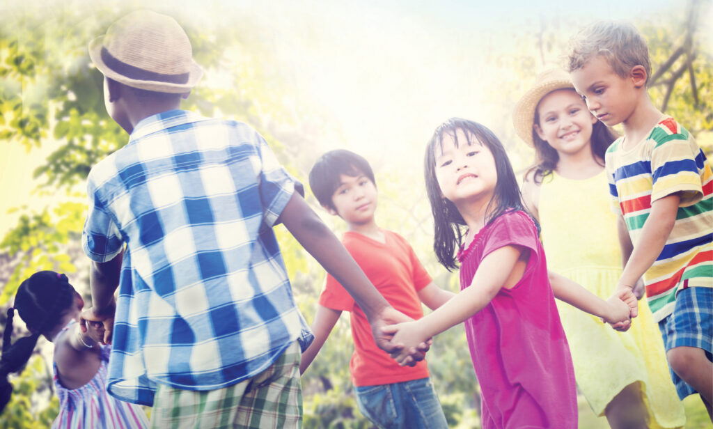 Children playing outdoors hold hands in a circle