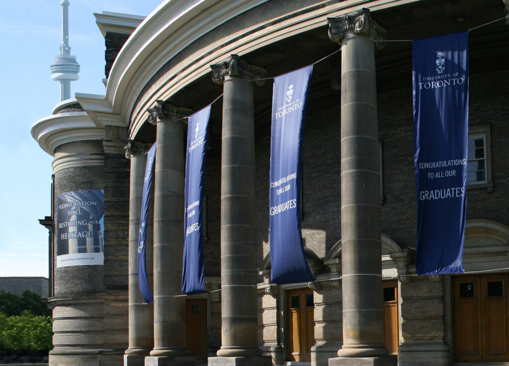 Banners hang on the pillars outside Convocation Hall. They read: Congratulations to all our graduates, University of Toronto.