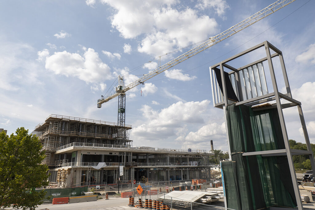 A construction crane looms over a construction site and the concrete skeleton of a building.