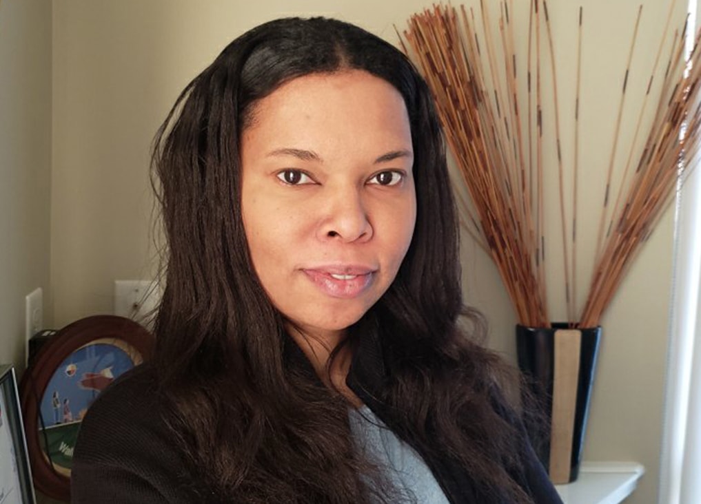 Erica Neeganagwedgin smiles as she sits in an office decorated with artwork and bamboo.