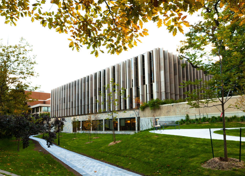 The Faculty of Law Building features rows of vertical concrete fins between the windows, and a green space with walkway..