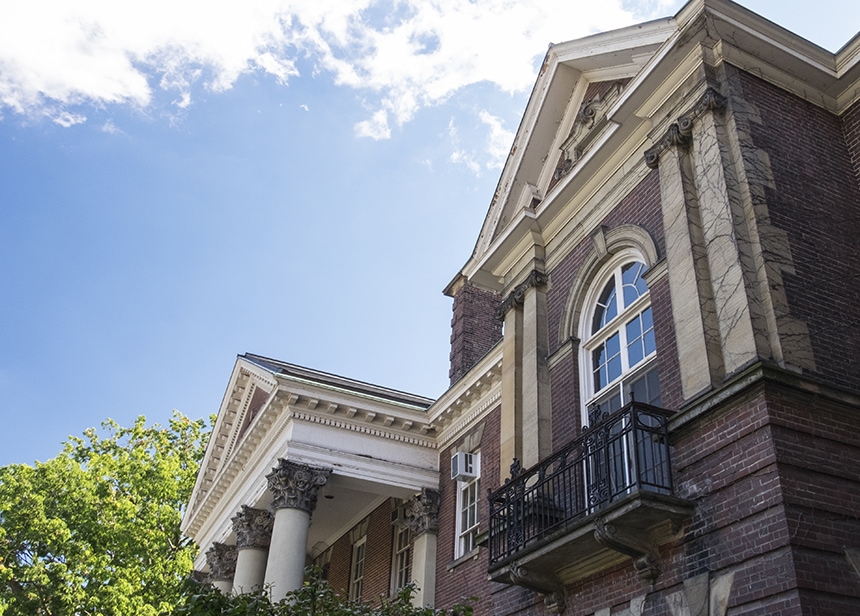 The roofline of Flavelle House, with columns and pediments, is seen against a sunny sky.