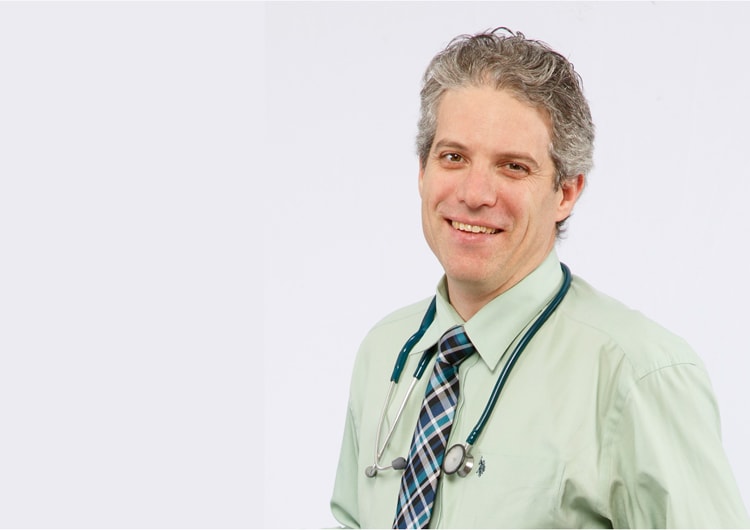 Portrait of Jonathon Maguire smiling and wearing a stethoscope around his neck.