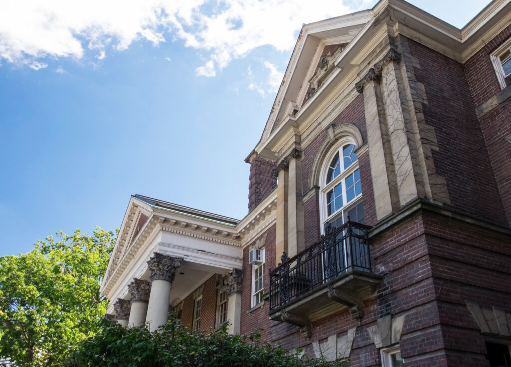 Ornate pillars and a an iron balcony decorate the law building, seen against a sunny sky.