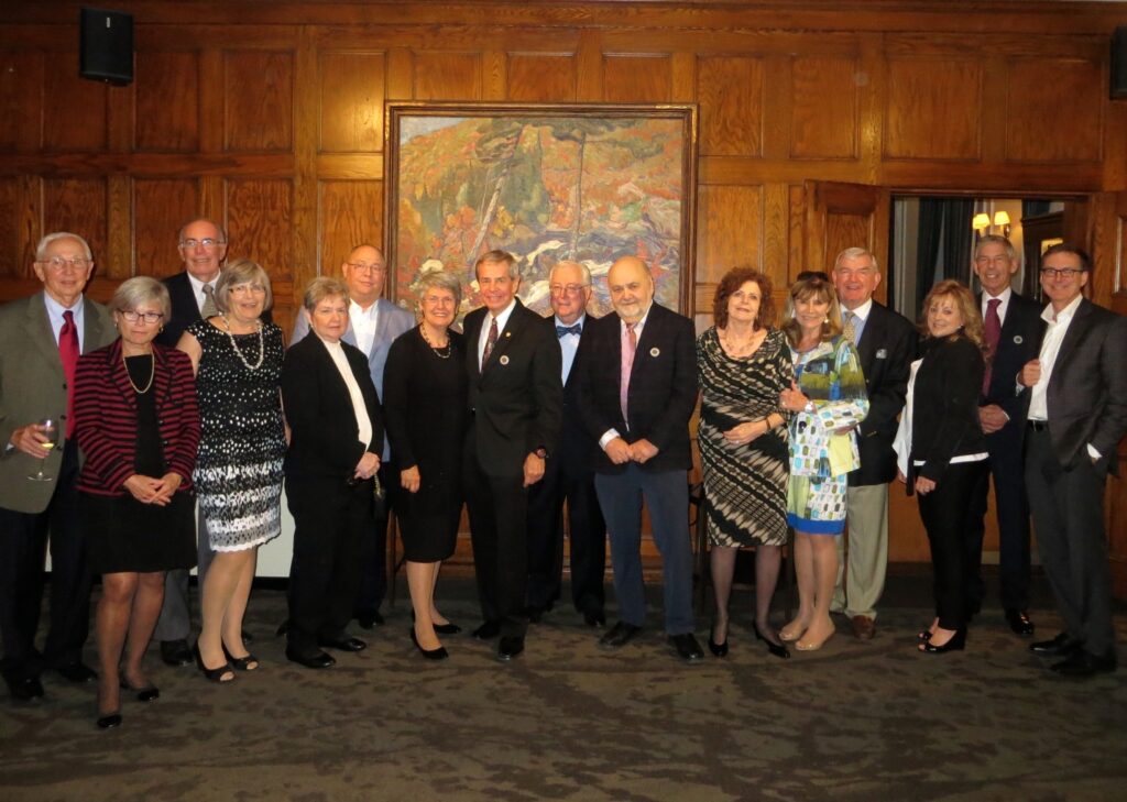 Several members of the MBA Class of 67 and their partners pose for a picture at a party.