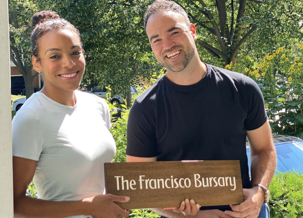 Mike and Quinn Samardzic smile happily as they hold up a sign that says: the Francisco Bursary.