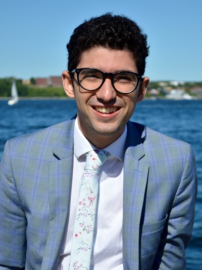 Nick Fernandez smiles while standing on a dock beside an ocean inlet.