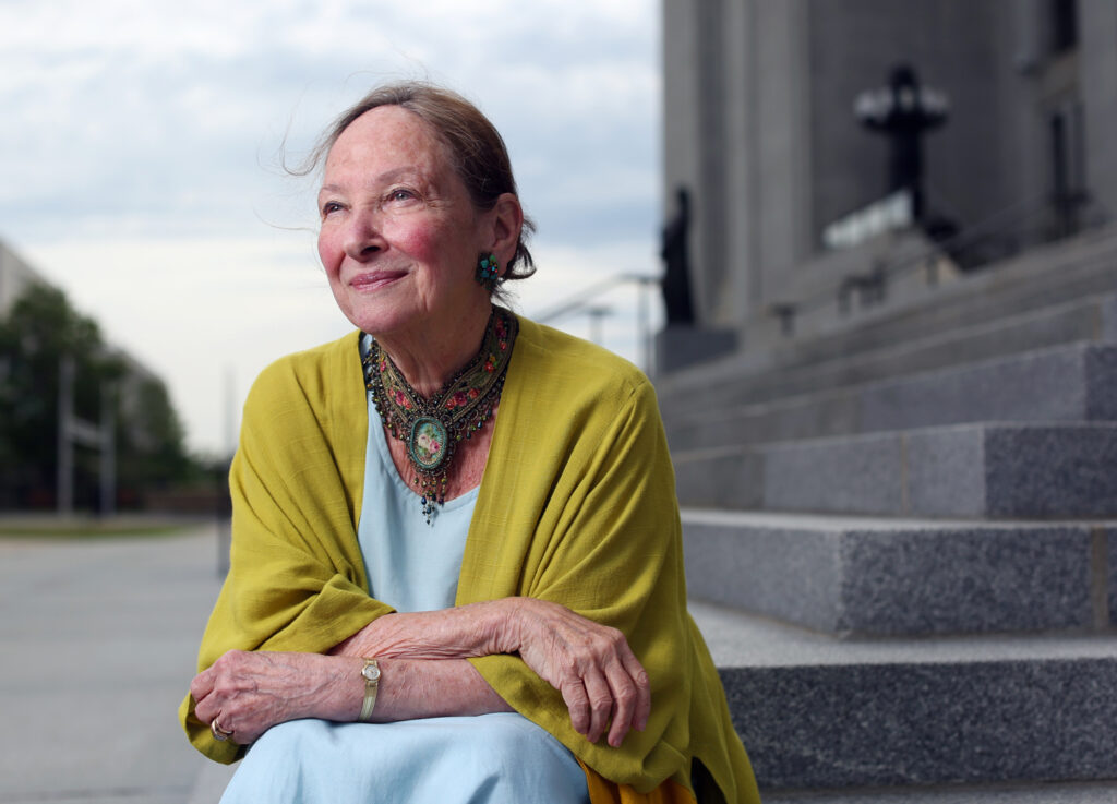 Rosalie Silberman Abella smiles, looking out at the horizon, as she sits on the stone steps outside the Supreme Court.