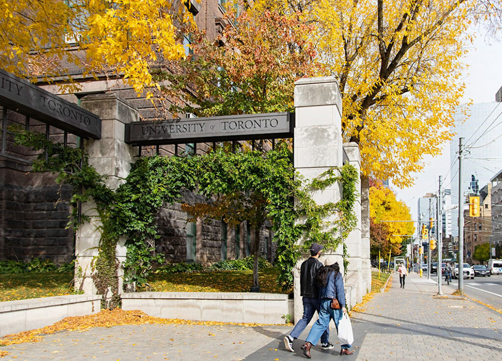 Metal beams (engraved with the words University of Toronto) rest across stone pillars to form U of T’s Alumni Gates.
