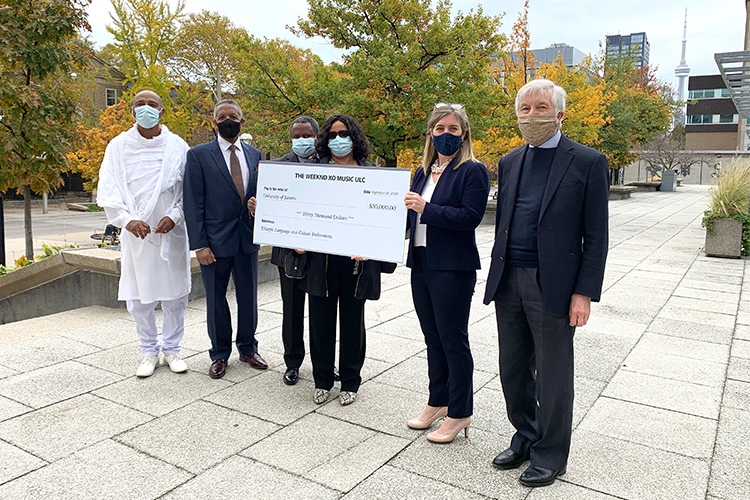 Two community representatives, The Weeknd's parents, and two U of T representatives stand with a large-sized cheque.