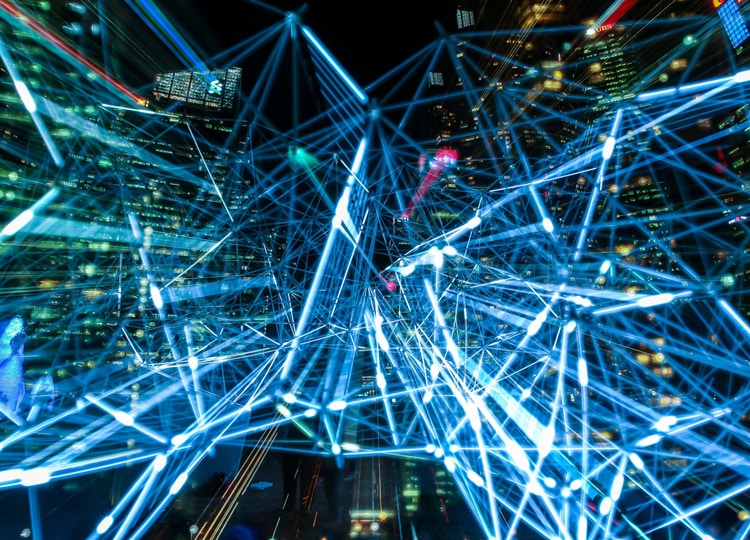 A tangled mass of streaks of light, in front of office buildings at night.