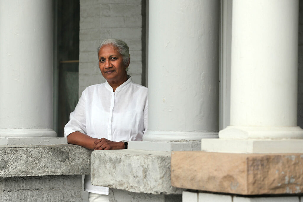Women's studies founder Ceta Ramkhalawansingh, leaning on a stone column outside a building.