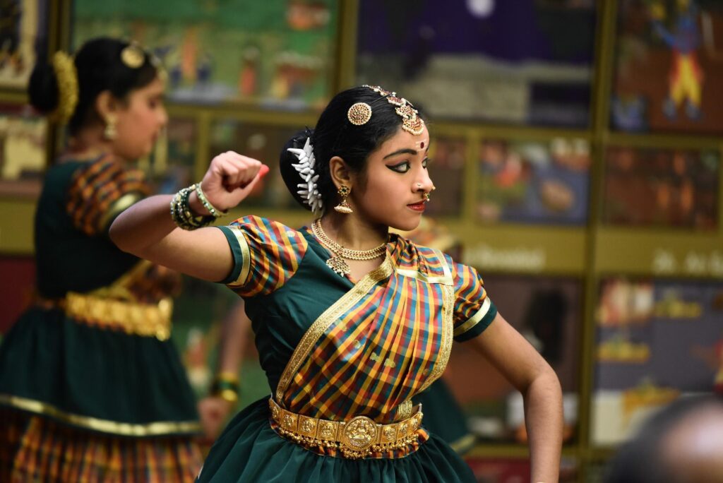 A dancer from Shilompoli Shethra Dance Academy, raises her hand in a traditional Tamil dance.