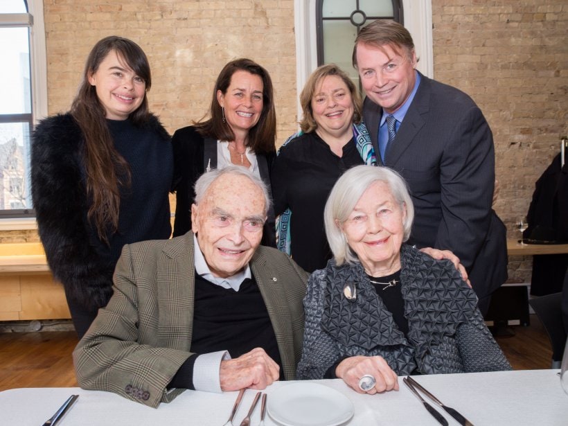 Eberhard and Jane Zeidler smile, sitting at a table with their four adult children standing behind them.