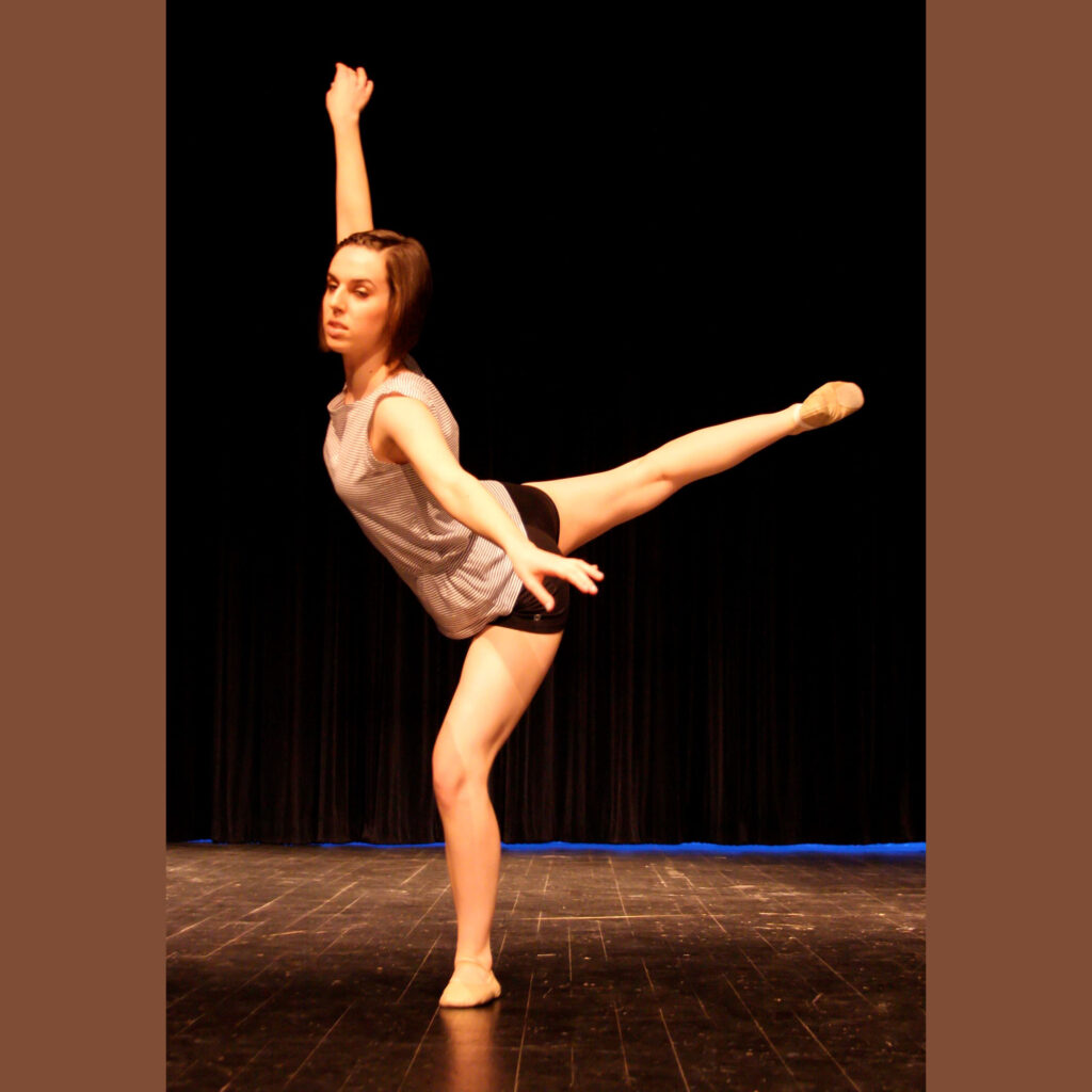 Sarah Harris in a ballet pose with arms lifted and one leg stretched high behind.