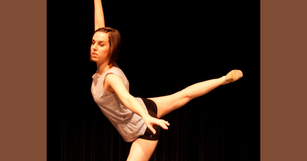 Sarah Harris in a ballet pose with arms lifted and one leg stretched high behind.