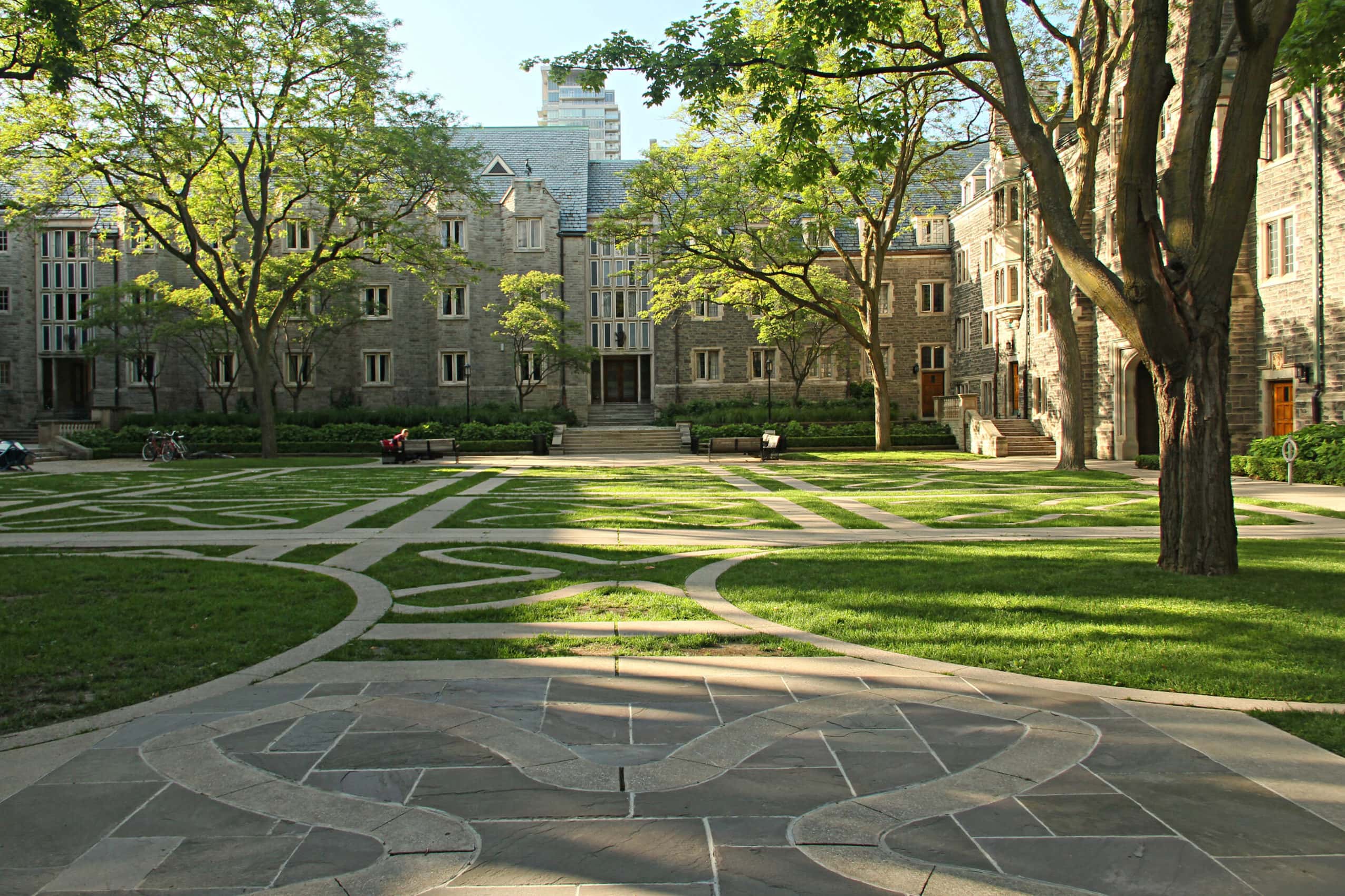 The Trinity Quad is a lush lawn with trees, criss-crossed with stone pathways, enclosed in old stone buildings.