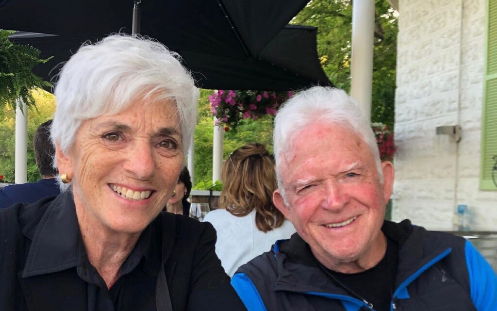 Julia and Michael Sax smile in a selfie on a restaurant patio.