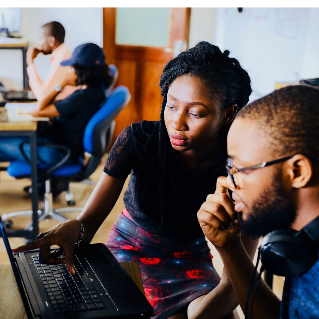 A Black man and woman look intently at a computer screen together.