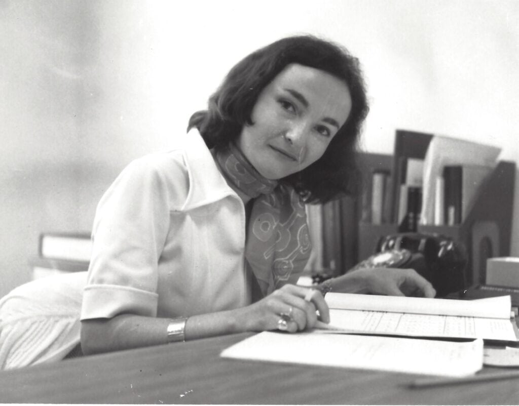 In a photo from 1977, Marilyn Hernandez looks up from reading papers at her desk.