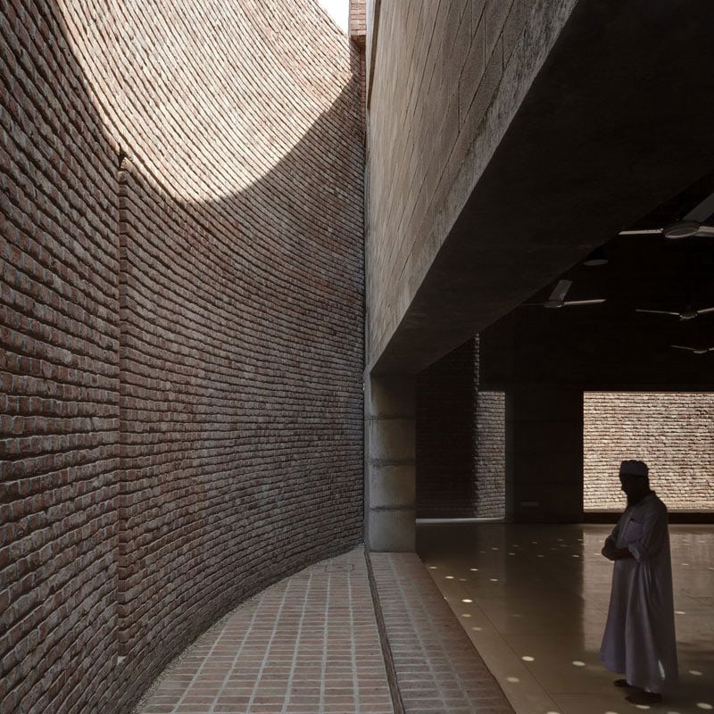 Light falls through curved opening onto the interior brick wall of the Bait ur Rouf Jame Mosque.