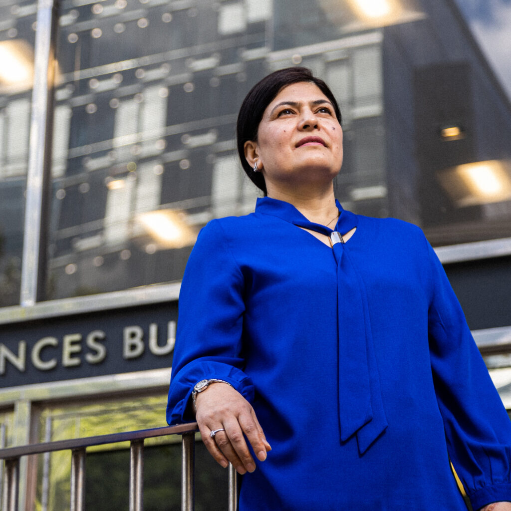 Basnama Ayaz stands tall on the steps of the Bloomberg Nursing building, looking up.