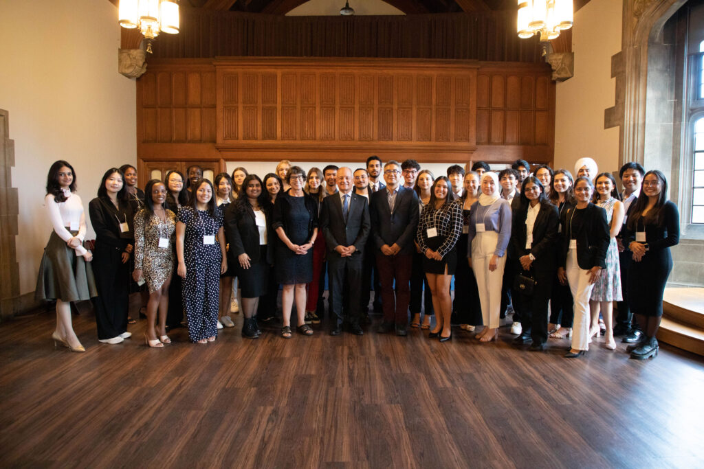 The 37 new Pearson Scholars pose for a group photo in a large room with stone archways and wood paneling.