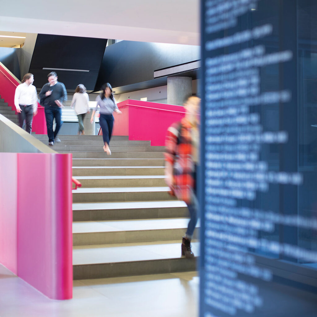 In a time-lapse photograph, students walk down the iconic pink stairs at the Rotman School of Management.