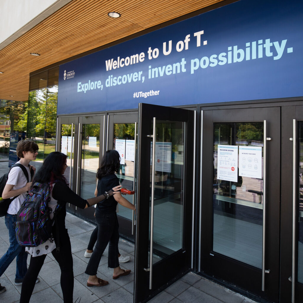 Students enter a building beneath a banner: Welcome to U of T. Explore, discover, invent possibility.
