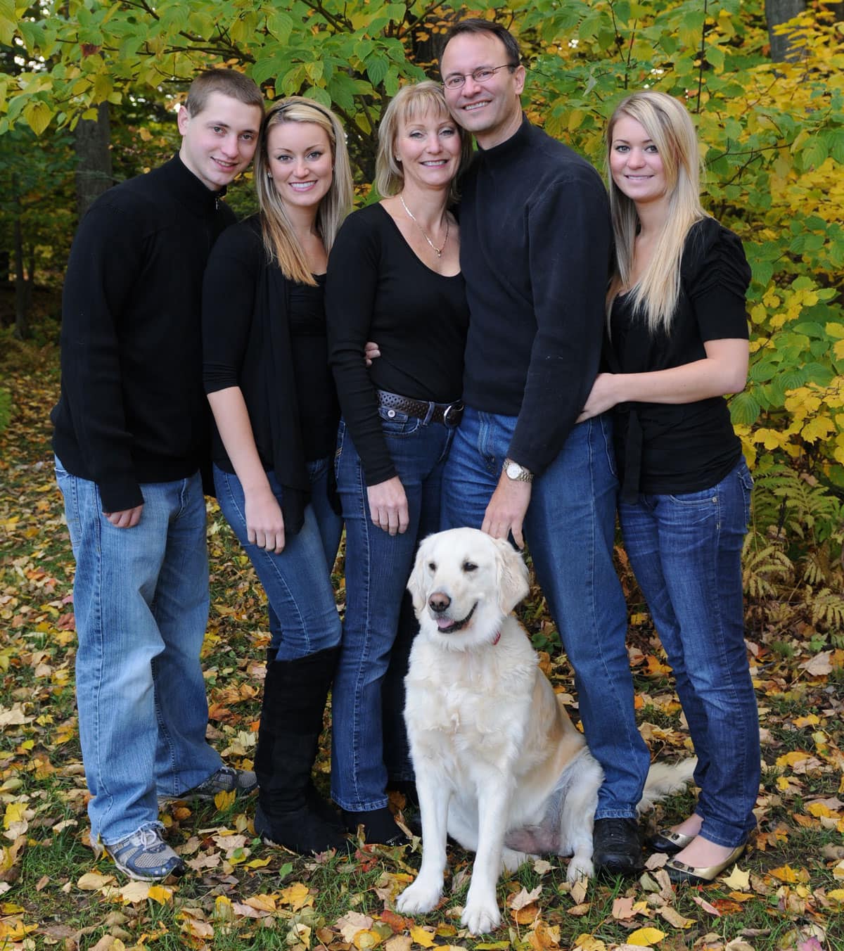 Carl and Christina Walker with arms around each other, surrounded by their three children and dog..