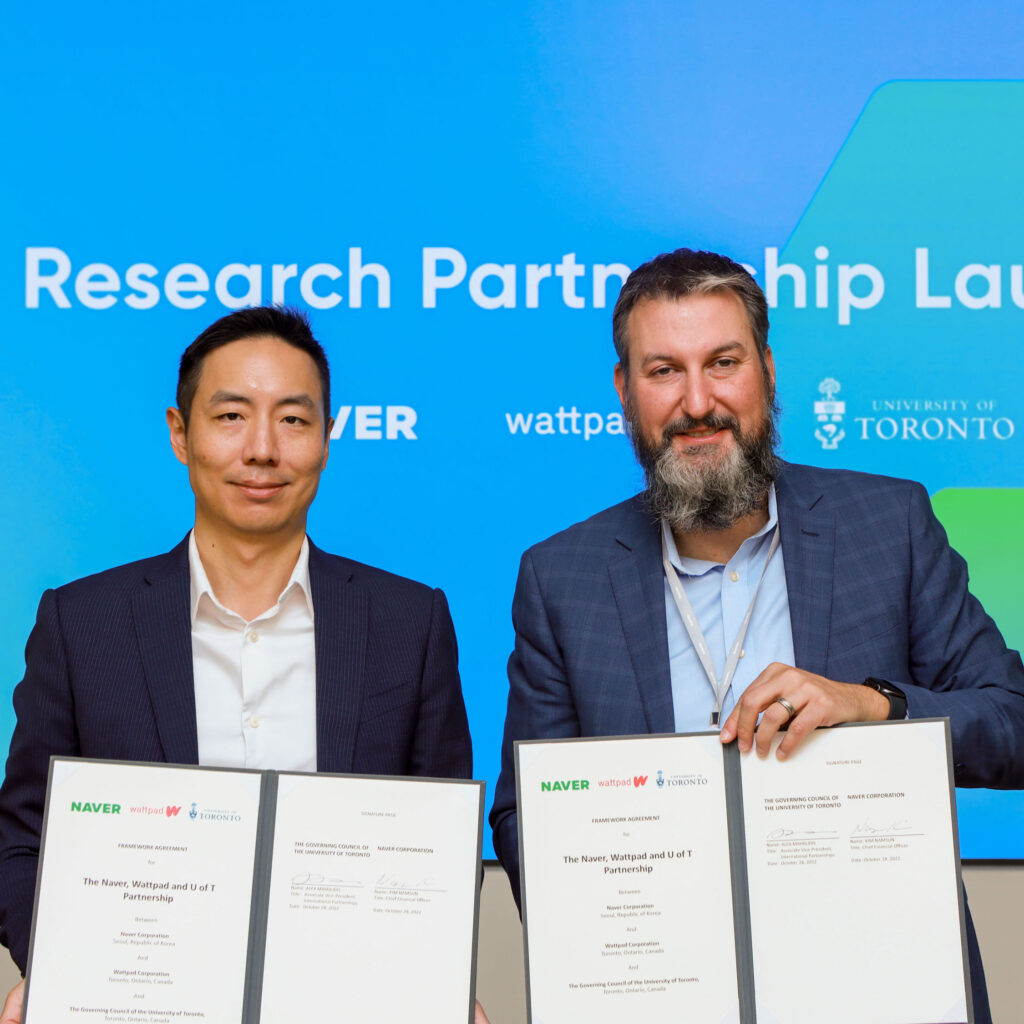 Namsun Kim of Naver and Alex Mihailidis of U of T, smiling under a sign that says, Research Partnership Launch.
