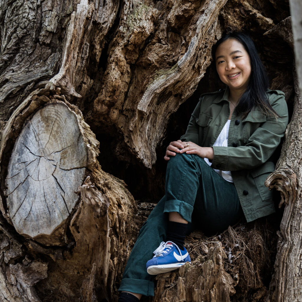 Amélie Desroches smiles as she sits inside a hollow in the trunk of an enormous tree.