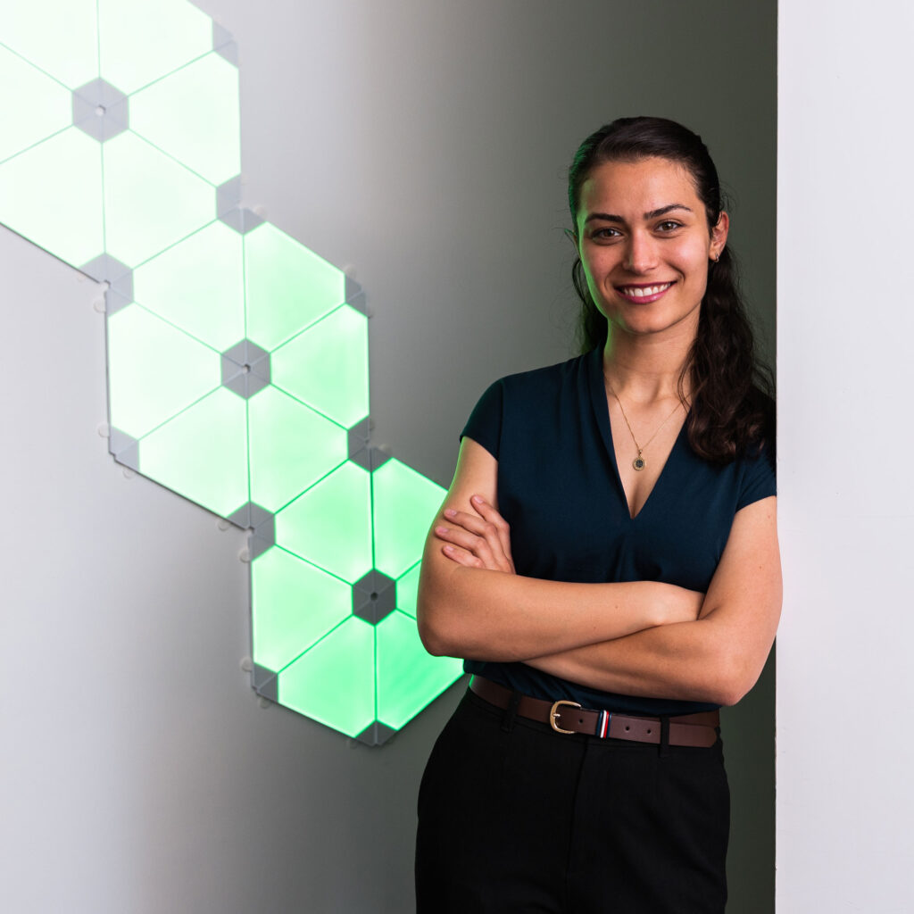 Jessica Jenkins smiles, standing in front of a glowing geometric design at the OnRamp hub.