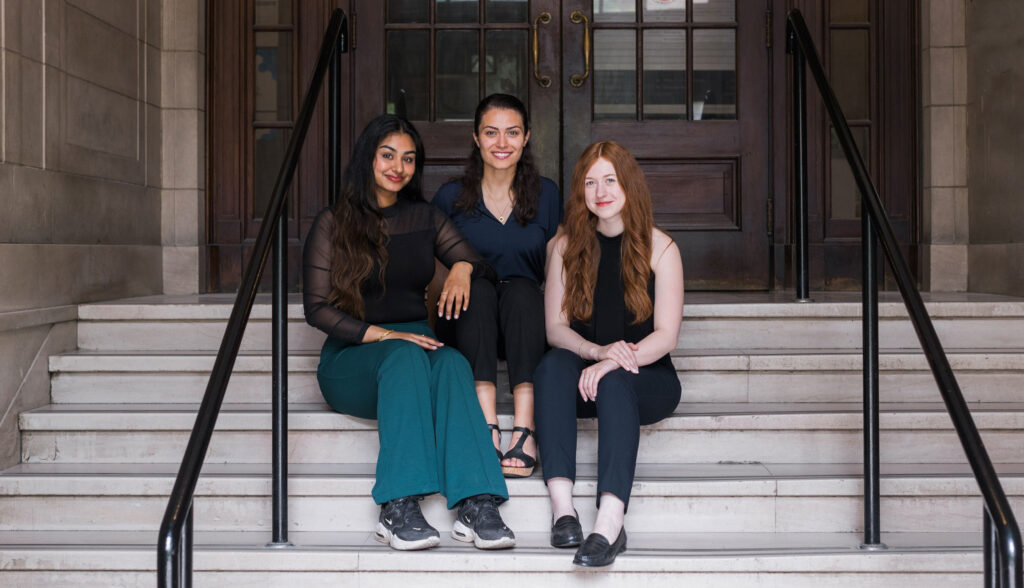 Jessica Jenkins, Jaspreet Randhawa and Siobhan Wilson sitting on a staircase, all smiling.