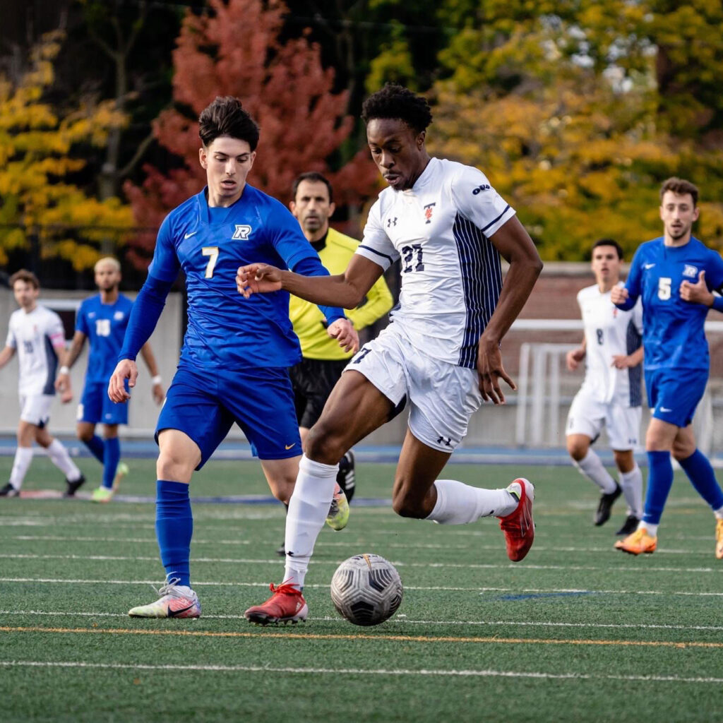 Kingsley Belele, in Varsity Blues uniform, races up a soccer field with the ball