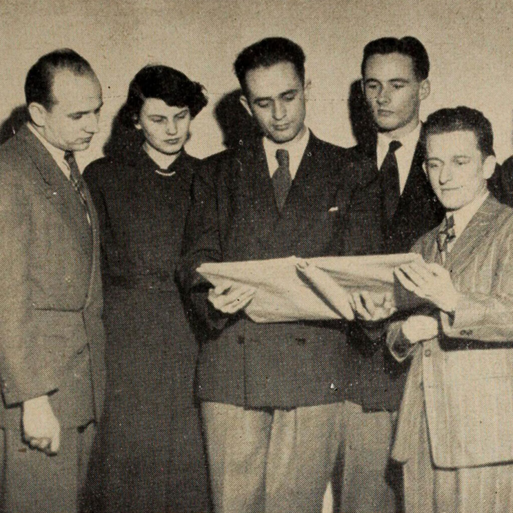 Joyce Sowby and four men look quizzically at an open binder.