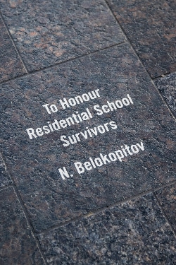 A paving stone engraved with the words: To Honour Residential School Survivors, N Belakopitov
