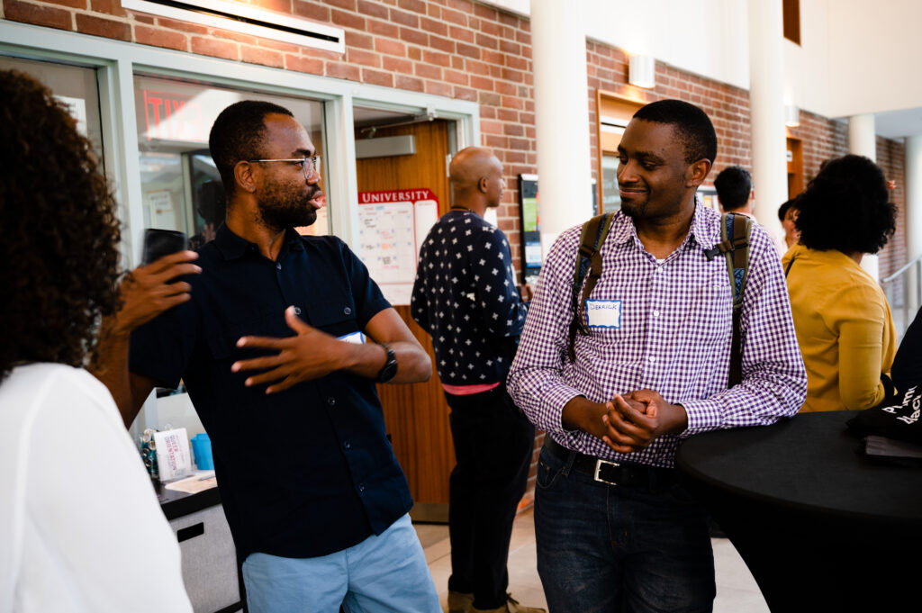 Two Black men chat animatedly at a BRN Welcome Social event.