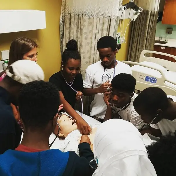 Students gathered around a hospital bed